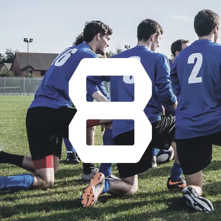 Soccer players in blue jerseys kneel on a grassy field, number 8 prominently overlaid.