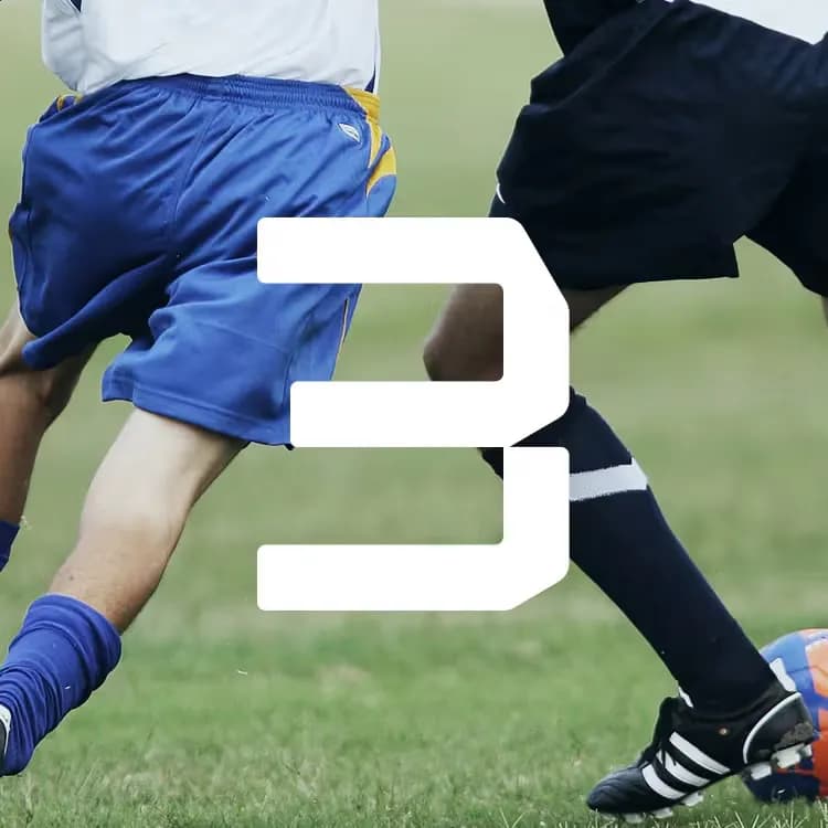 Two soccer players in action, one in blue and the other in black, competing for the ball on a grassy field. White number 3 overlay.